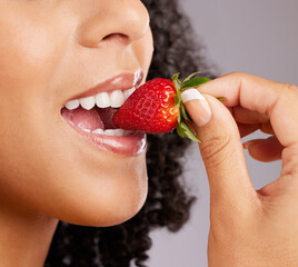 Woman, mouth and eating strawberry for natural nutrition, dieting or healthy food against a gray studio background. Closeup of female lips enjoying tasty organic fruit for health, diet or wellness