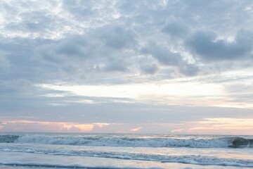 Fototapeta na wymiar Scenic shot of foamy waves of the sea crashing the shore at sunrise