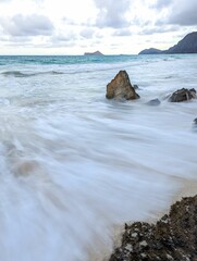Vertical shot of the ocean waves crashing on the rock in Rabbit, Waimanalo Beach, Oahu, Hawaii