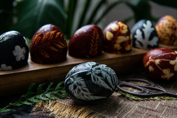 Easter eggs dyed with natural ingredients like cabbage, onion peel, hibiscus tea carcade with beatiful patern on rustic wooden tray and craft paper.