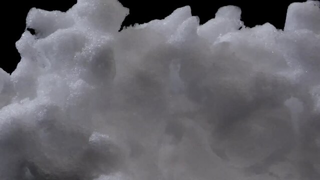 Time lapse of slowly melting snow on black background