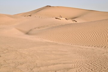 Scenic view of desert against sky under the clear blue sky with the sun shining bright