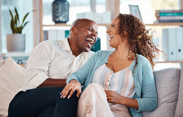 Love, happy and couple laugh on sofa for bonding, quality time and relaxing together at home. Marriage, interracial relationship and man and woman on couch embrace, hugging and laughing at funny joke