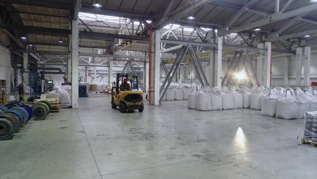 Forklifts in a large warehouse, active workflow in the warehouse. Forklifts move in a large bright warehouse