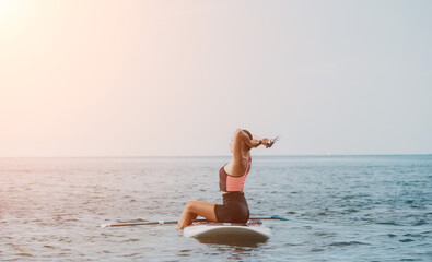 Fototapeta na wymiar Sea woman sup. Silhouette of happy young woman in pink bikini, surfing on SUP board, confident paddling through water surface. Idyllic sunset. Active lifestyle at sea or river.