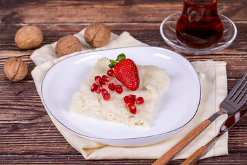 Güllaç dessert with pomegranate and strawberry. Ramadan dessert. Gullac dessert with walnuts on wooden background.