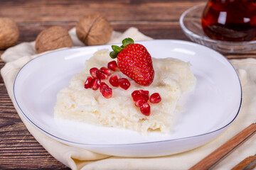 Güllaç dessert with pomegranate and strawberry. Ramadan dessert. Gullac dessert with walnuts on wooden background. Close up
