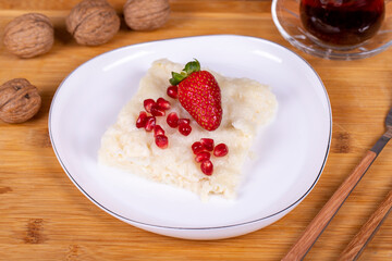 Güllaç dessert with pomegranate and strawberry. Ramadan dessert. Gullac dessert with walnuts on wooden background.