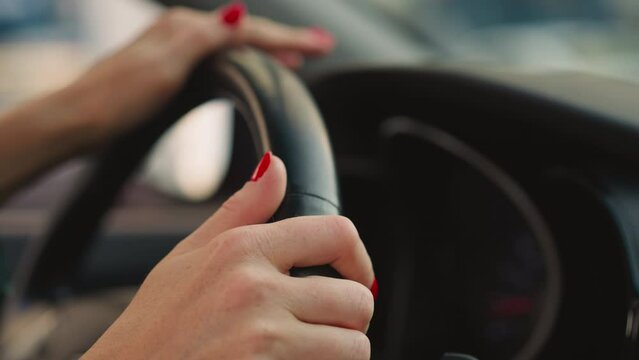 Woman turns steering wheel of car to sides moving fingers
