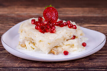 Güllaç dessert with pomegranate and strawberry. Ramadan dessert. Gullac dessert with walnuts on wooden background. Close up