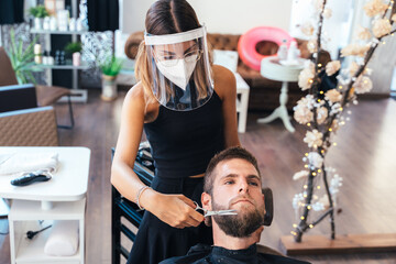 Hairdresser trimming the beard of a client in a salon