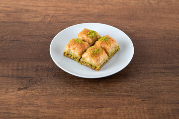 Turkish baklava with pistachio in plate.A plate baklava on wooden background,top view
