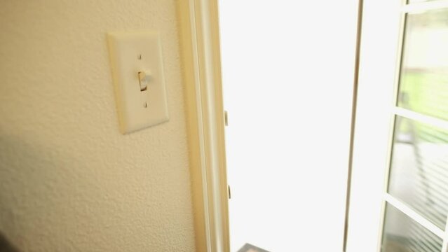 Medium shot of hand opening white door revealing bright sunlight from house backyard.