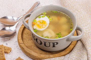 Meatball soup with boiled egg, ditalini pasta, vegetables and fresh herbs. Healthy chicken broth