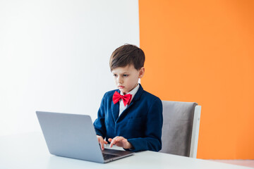 schoolboy boy sitting at a laptop at a desk in a school in a classroom online education room