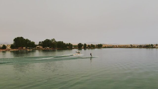 Male wakeboarder early morning glassy water lake behind boat drone follow