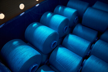 Fototapeta premium Blue rolls of industrial cotton in weaving factory, hand weaving cotton for the fashion and textiles industry. Yarn weave traditional textile fabric manufacturing for clothing and fashion.