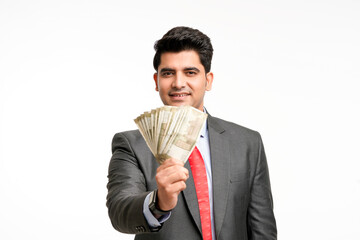 Young indian man in suit and showing indian rupees on white background.