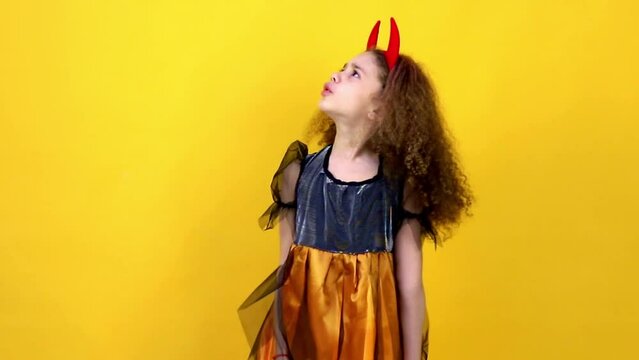 A young girl on a yellow background shows emotions, the concept of the holiday Halloween