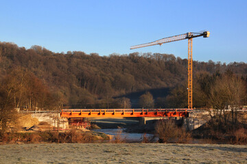 Crane on the construction site of a provisional bridge after Pr&uuml;m river flood in Minden village, Eifel region in Germany