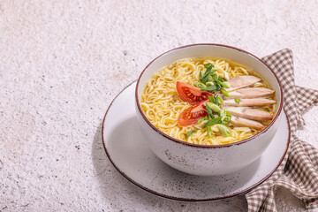 Spicy noodles with beef broth. Hot dish, cutlery, hard light, dark shadow. Stone concrete background