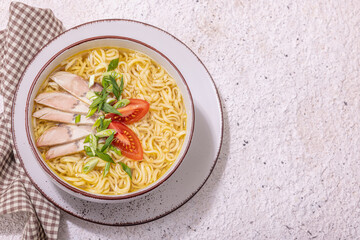 Spicy noodles with beef broth. Hot dish, cutlery, hard light, dark shadow. Stone concrete background