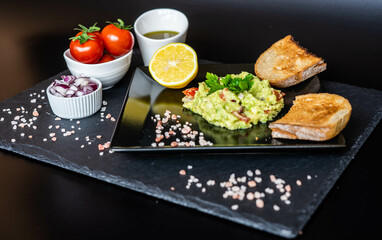 Homemade guacamole with red onion, cherry tomatoes, olive oil, pink salt and lemon juice,...