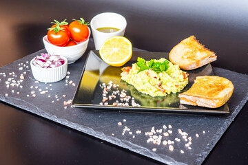 Homemade guacamole with red onion, cherry tomatoes, olive oil, pink salt and lemon juice, accompanied by toast . Home cooking, eating healthy, vegan food