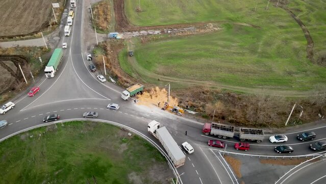 Car crash traffic accident: wheat grains scattered along road after breaking overturning cargo truck. Huge traffic jam. Road safety and insurance concept