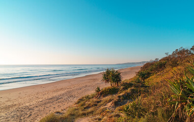 Beautiful wide panorama of the Peregian Beach nestled against the dunes of a pristine white sand beach with surfing breaking waves on the Sunshine Coast, Queensland, Australia.