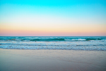 Mesmerizing sunrise over Pacific ocean and beautiful turquoise waves rolling in on a pristine sandy beach. 
