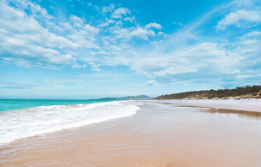 Stunning panoramic view of the ocean and beautiful waves rolling in on a pristine sandy beach. 