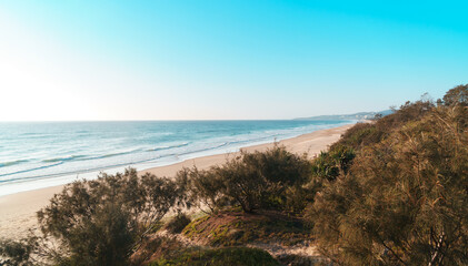 Amazing wide panorama of Peregian Beach on a sunny day. Spectacular beach background with blue turquoise water visible from the hill. Beautiful travel destination. Noosa, Sunshine Coast, Australia.