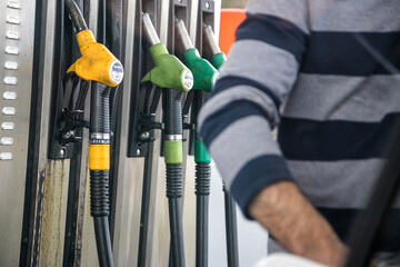 Person filling the fuel tank, highlighting the hoses of the different petroleum products that are...