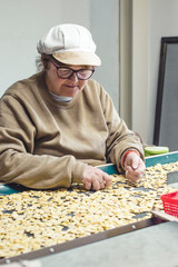 Working older woman selecting bean seeds