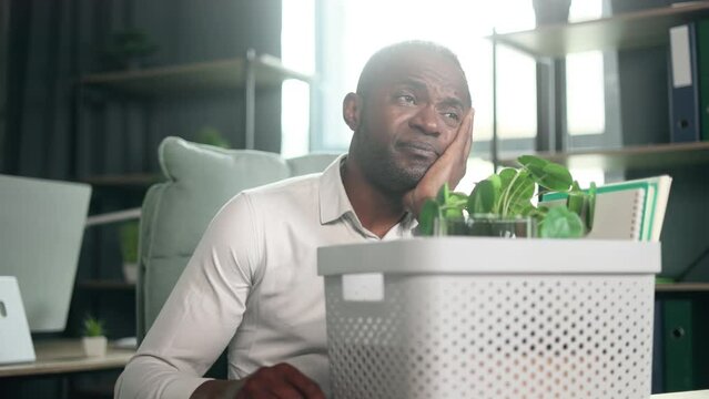 Portrait of fired sad african american businessman carries his box with personal belongings need to leave the office Pensive mature man thinking about future after unemployed looking around indoors