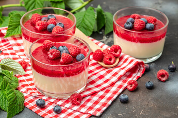 Delicious italian dessert panna cotta with berry sauce on a dark background in small jars. place for text