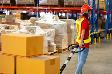 Warehouse female staff worker wearing hardhat helmet standing by goods shelf working pulling a...