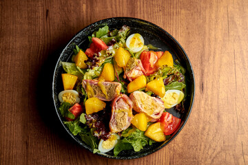 Salad with vegetables, herbs and grilled tuna. Nicoise salad. Wooden background