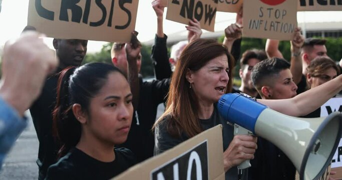 Group of multiracial people protest against inflation and financial crisis - Protesters marching for rise cost of living in the city - Mature woman screaming with megaphone