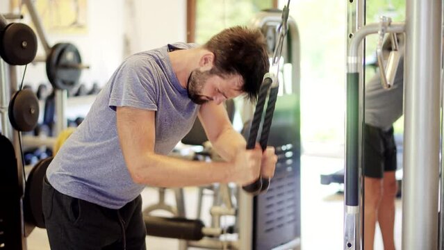 Man weight lifted exercising in gym cable pushdown