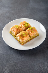 Pistachio Turkish baklava on a white plate.Close-up of four slices of baklava
