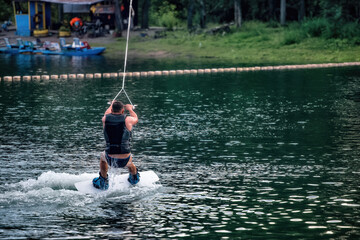 Naklejka premium A man wakeboarding on a lake on summer day in a life jacket. Soft focus. Action blur.