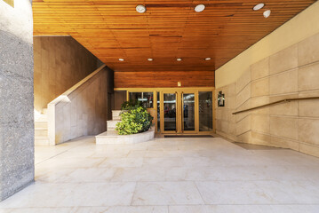 exterior access portal to a residential building with golden metal doors, wooden coffered ceiling...