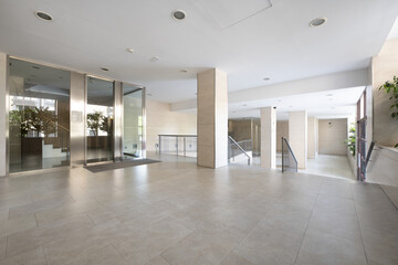 Exterior street portal of a residential building with cream marble flooring and gray tiles and metal and glass halls