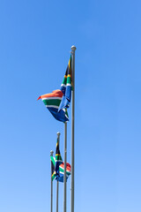 3 flags of South Africa waving in the wind against a blue sky background