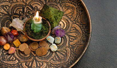 Witch altar. candle, different old coins, stone runes, crystals in plate on dark abstract  background. Magic ritual for attracting money, wealth. witchcraft esoteric practice. top view