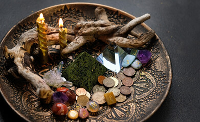 Witch altar. candles, different old coins, stone runes, crystals in plate on dark abstract ...