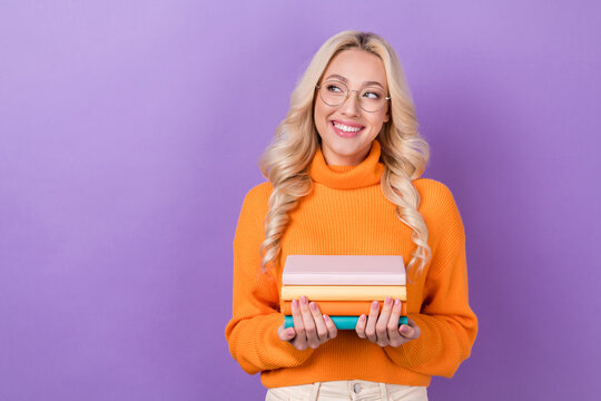 Portrait of cheerful intelligent lady hands hold pile stack book look empty space isolated on purple color background
