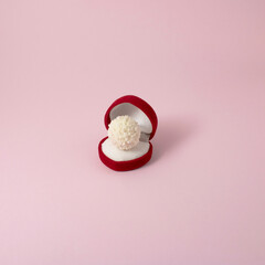 Love composition made of hert red engagement ring box with white chocolates on pink pastel background. Minimal creativ love concept.